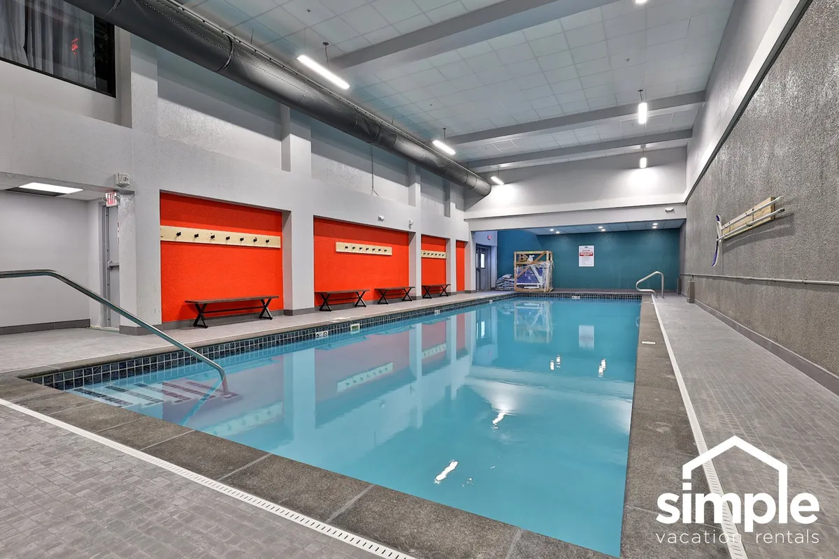 An inviting indoor swimming pool with vibrant, colorful wall panels and comfortable benches along the edge, creating a lively atmosphere perfect for relaxation and refreshing swims. The space feels energetic yet tranquil, suitable for socializing or quiet moments by the water.