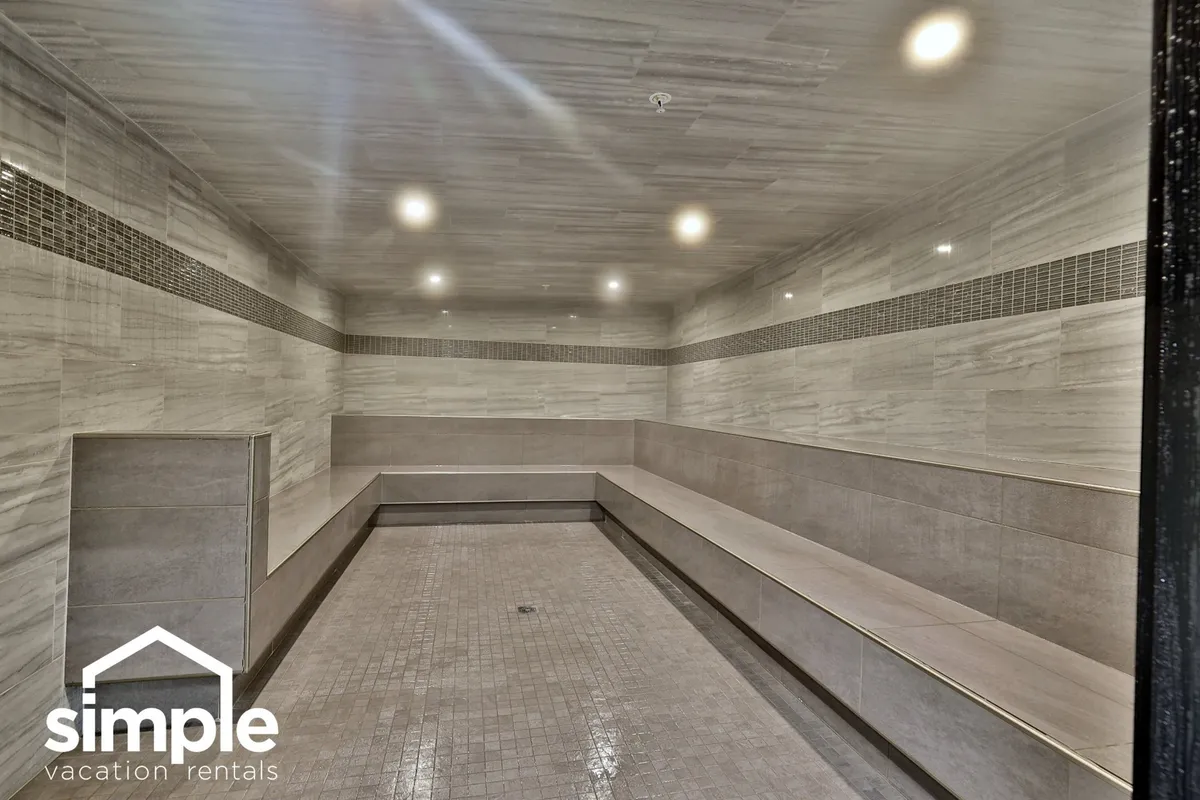 A tranquil steam room with sleek marble walls, built-in benches, and gentle overhead lighting. The space exudes peace and facilitates relaxation, offering an authentic spa-like environment for guests to unwind.