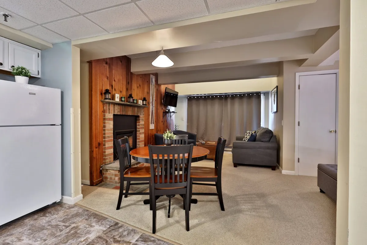 The view includes a dining table next to a kitchen area and a cozy living space with a fireplace and sofa, capturing both the dining and kitchen zones in a single frame.