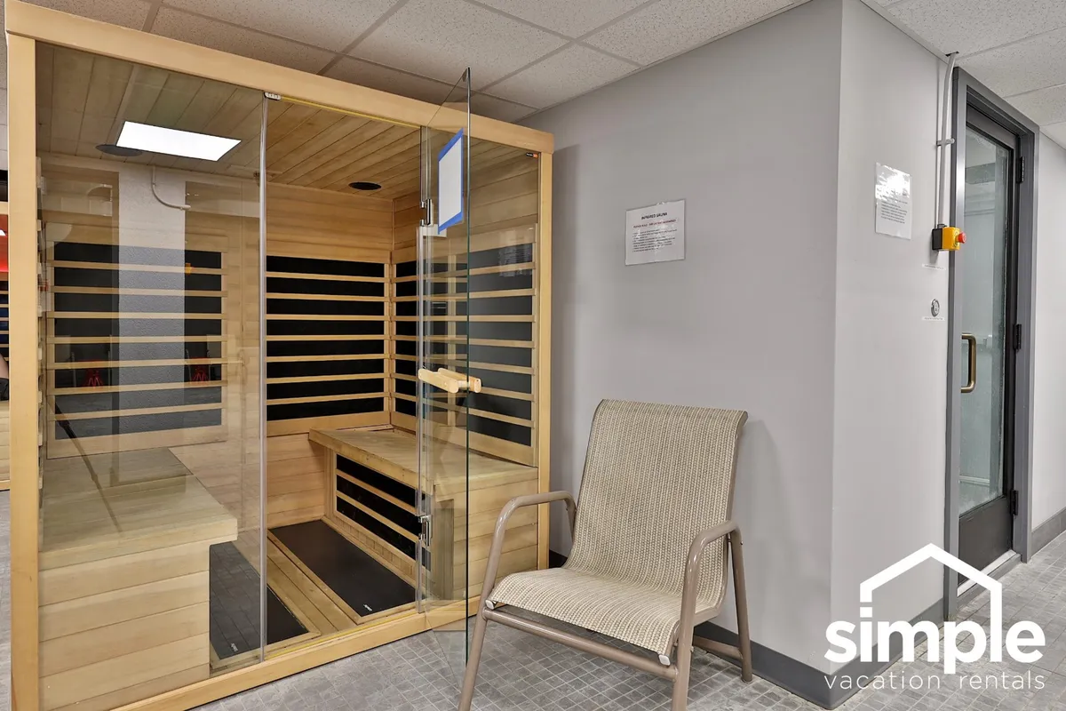 A serene sauna room with natural wood benches and a calming ambiance, inviting guests to enjoy the restorative benefits of heat therapy. The minimalist décor and soft lighting evoke a tranquil spa-like atmosphere.